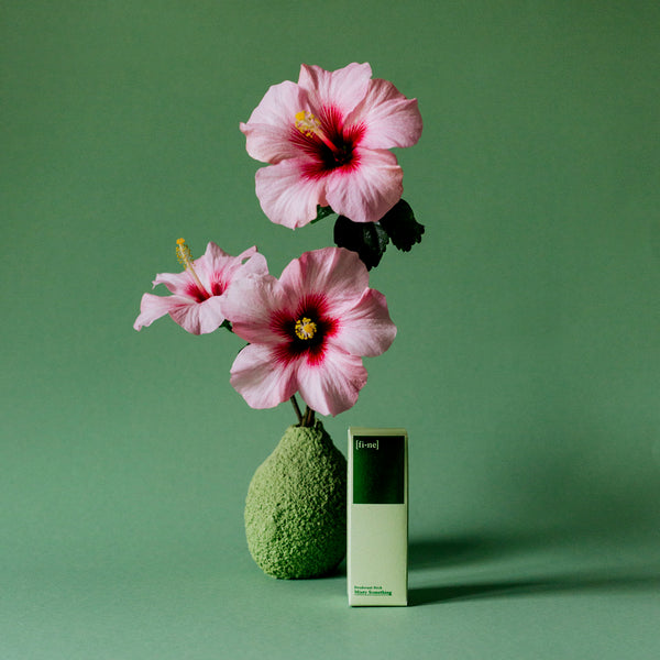 Minty Something Deo Stick in der Faltschachtel neben Hibiskusblüten